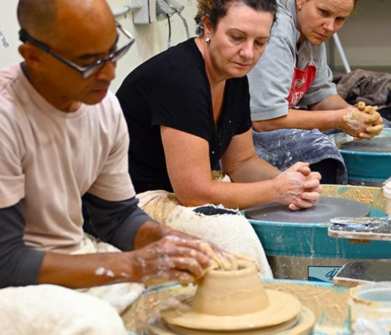 Decorative image - people sitting at pottery wheel