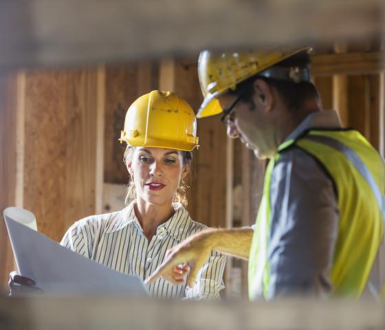 Decorative Image - Workers talking at construction site reviewing plans